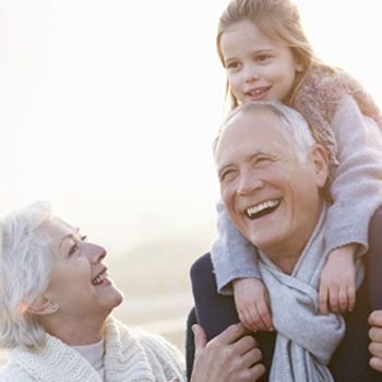 Grandparents walking, with little girl riding on grandfather's shoulders