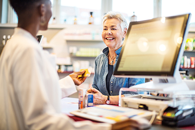 Older woman standing talking with pharmacist at counter