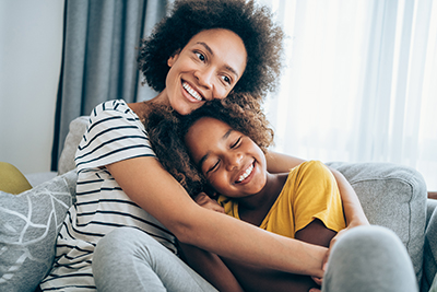 Woman and girl hugging on couch